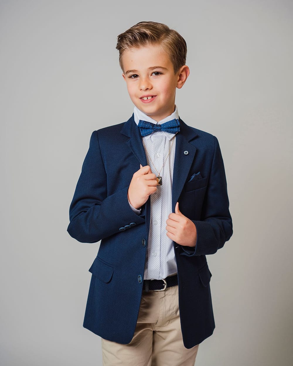 Niño con americana azul y pajarita en un retrato de comunión en el plató · Objectiu Fotògrafs, Reus