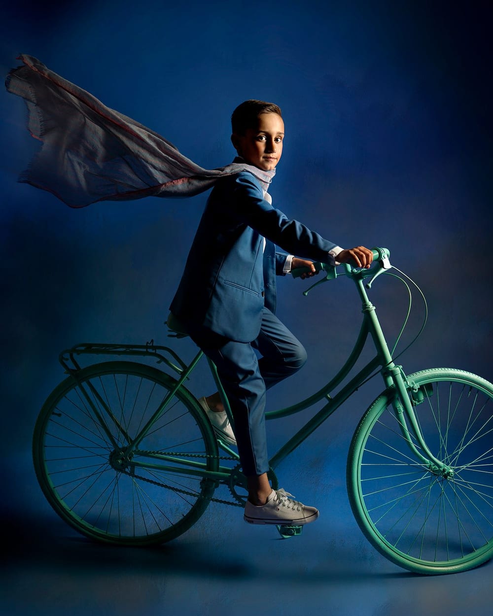 Niño con traje de comunión en una bicicleta, con la capa al viento · Objectiu Fotògrafs, Reus