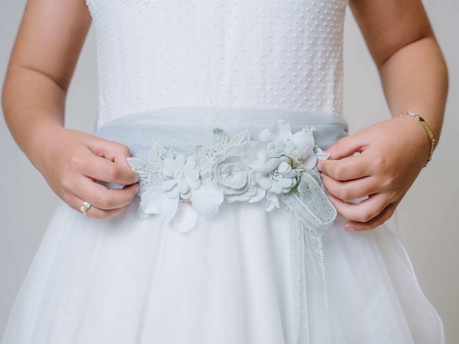 Manos de una niña sobre el cinturón de flores del vestido de comunión · Objectiu Fotògrafs, Reus
