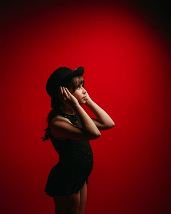 Niña con sombrero negro sobre fondo rojo en una sesión de comunión · Objectiu Fotògrafs, Reus