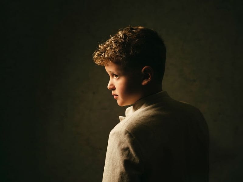 Perfil de un niño con americana clara, iluminado con luz cálida · Objectiu Fotògrafs, Reus