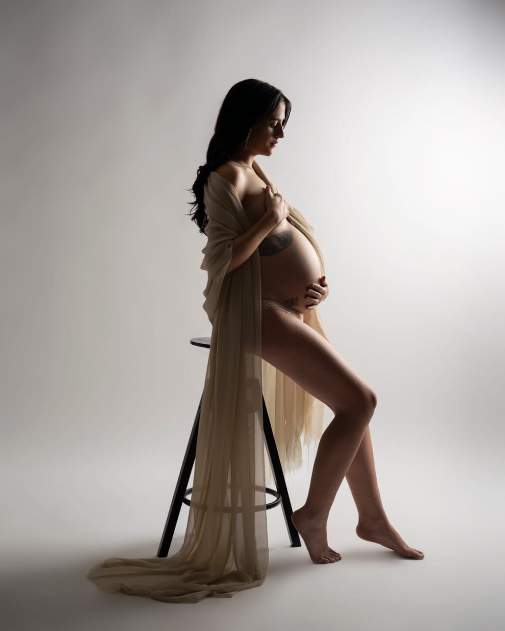 Studio maternity session, backlit against a light background · Objectiu Fotògrafs, Reus