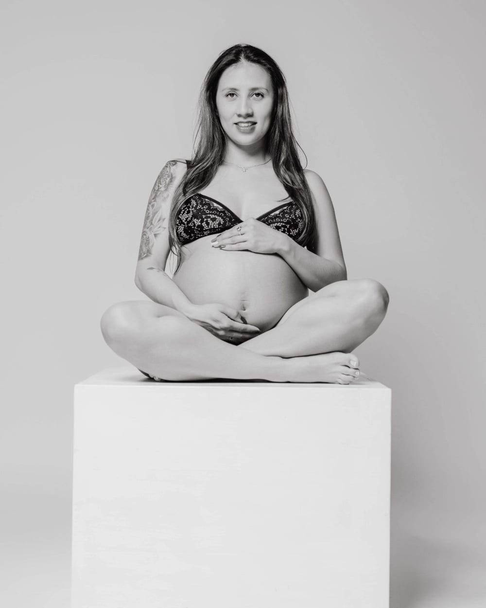 Pregnant woman sitting on a white cube, in black and white · Objectiu Fotògrafs, Reus