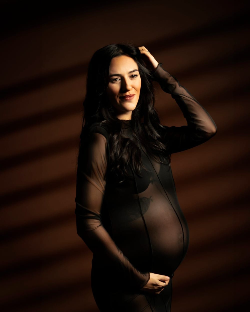 Pregnant woman in a sheer black dress on a dark backdrop · Objectiu Fotògrafs, Reus