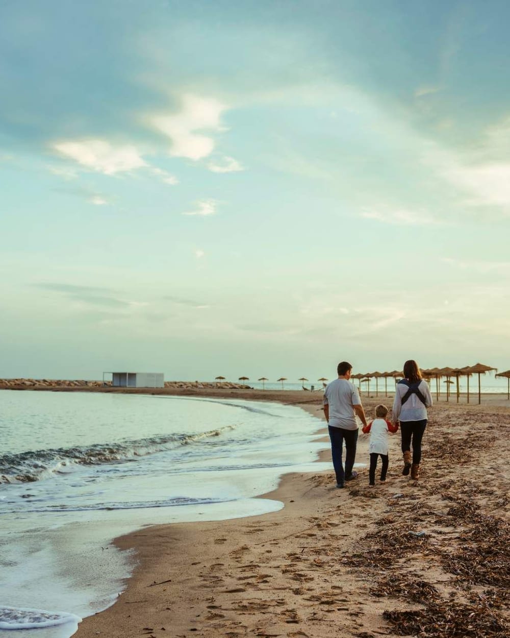 Family walking along the beach at sunset · Objectiu Fotògrafs