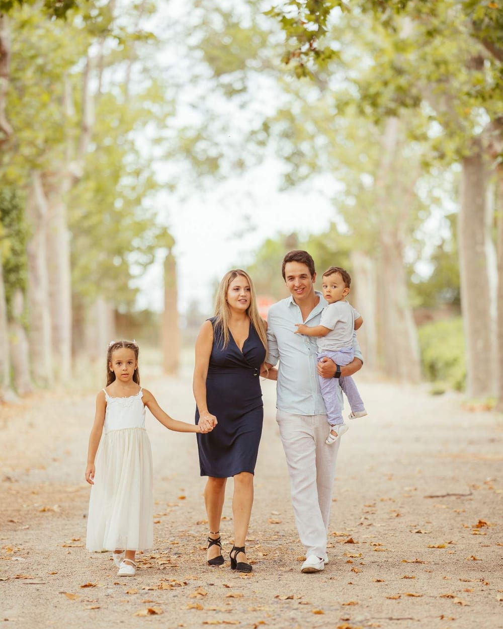 Família passejant per un camí d'arbres en una sessió a l'exterior · Objectiu Fotògrafs