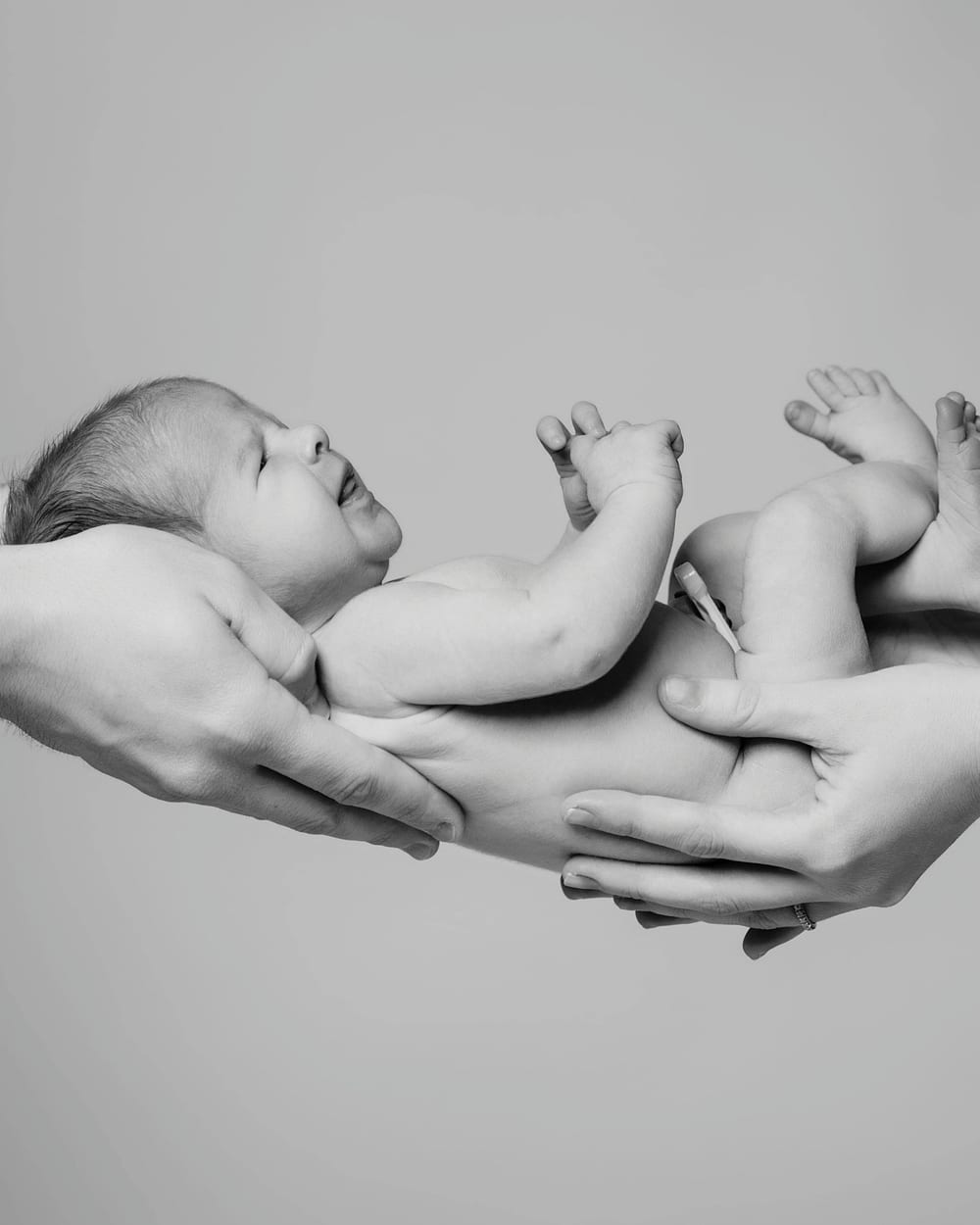 Bebé durmiendo en las manos de sus padres, en blanco y negro · Objectiu Fotògrafs, Reus