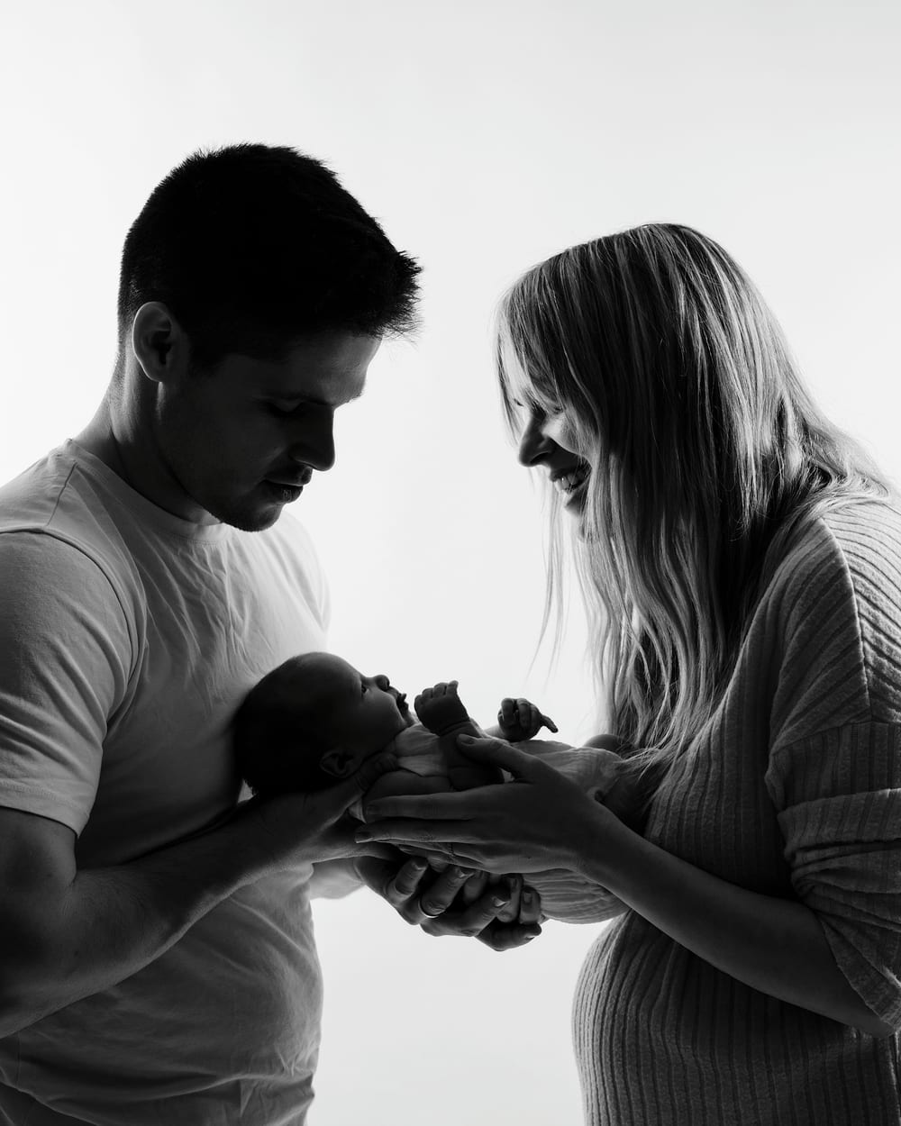 Silueta de los padres con el bebé en brazos, en blanco y negro · Objectiu Fotògrafs, Reus