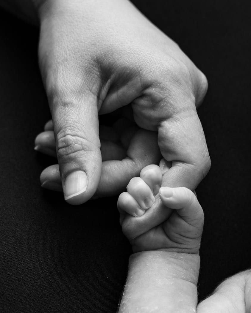 Mà adulta agafant la mà d'un nadó, en blanc i negre · Objectiu Fotògrafs, Reus