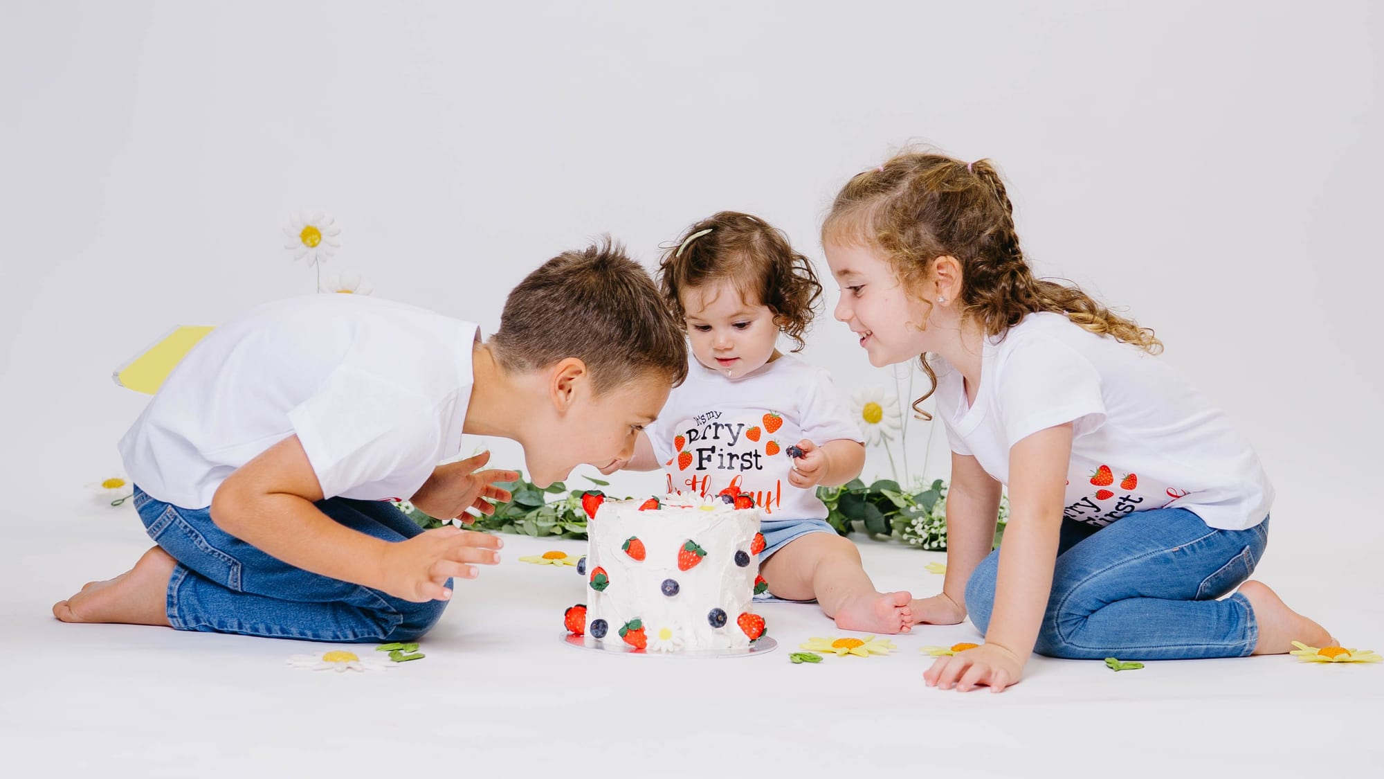 Tres germans al voltant d'un pastís en una sessió smash cake al plató · Objectiu Fotògrafs, Reus